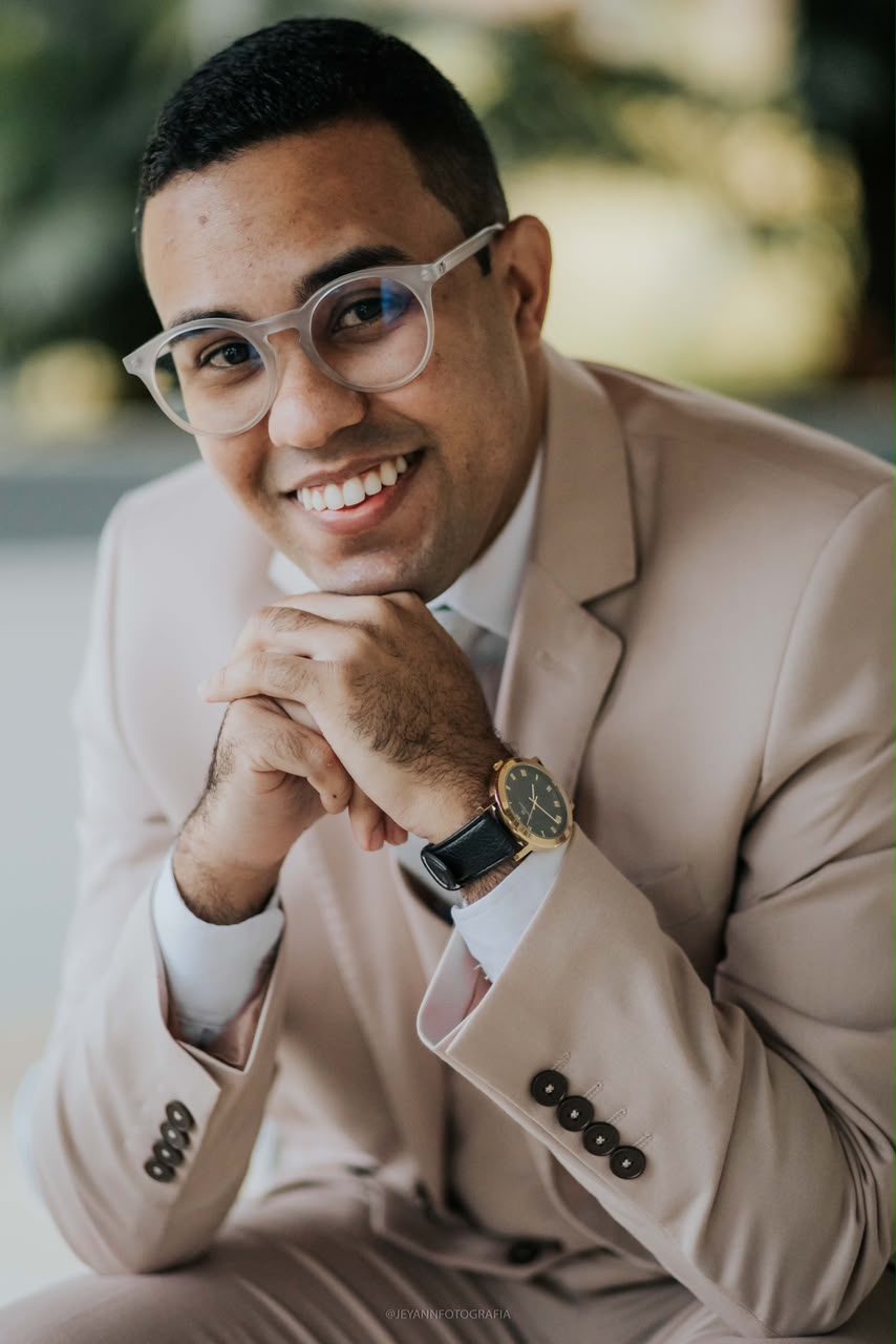 Pr. Amós Jubim sorrindo, usando terno claro e óculos
